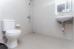 a white bathroom with a toilet and a sink at Urbanview Hotel Priority Samarinda by RedDoorz in Samarinda