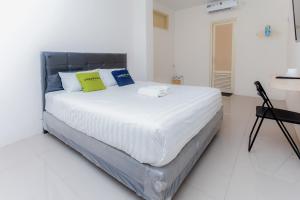 1 dormitorio con 1 cama blanca grande con almohadas amarillas y azules en Urbanview Hotel Priority Samarinda by RedDoorz en Samarinda