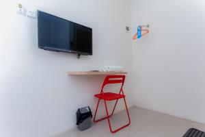 una silla roja en una habitación con TV de pantalla plana en Urbanview Hotel Priority Samarinda by RedDoorz en Samarinda