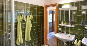 a green tiled bathroom with a sink and a mirror at Haus Schluchseeblick in Schluchsee