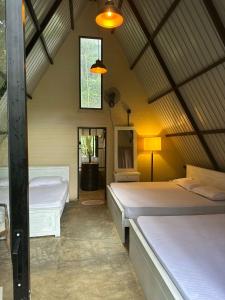 a bedroom with two beds and a window and a lamp at Pahiyan huts 