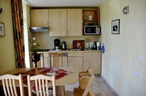 une cuisine avec une table en bois, une table et des chaises dans l'établissement 4 Sterne Apartment Dünensand Sauna und Terasse in Südwestlage, à Lobbe