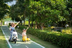 a woman and two children riding scooters down a street at SO/ Sofitel Hua Hin in Cha Am