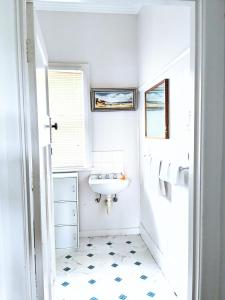 a bathroom with a white sink and a window at Hill’s Creek Holiday Home in Port Campbell