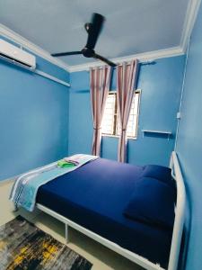 a blue bedroom with a bed and a window at Adam Homestay Besut in Kampung Raja