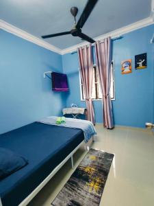 een blauwe slaapkamer met een bed en een plafondventilator bij Adam Homestay Besut in Kampung Raja