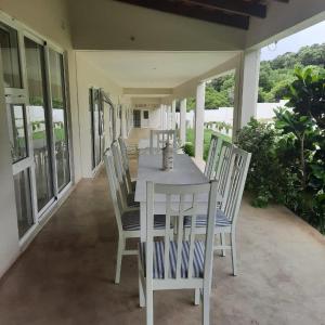 una mesa de comedor blanca y sillas en un patio en Tropicana Guesthouse en Ponta do Ouro