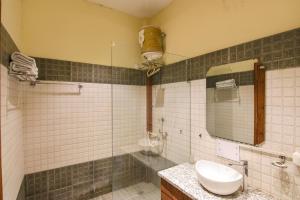 ein Bad mit einem Waschbecken, einem Spiegel und einer Dusche in der Unterkunft FabHotel K9 Regency in Dorāha