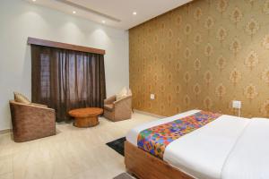 a bedroom with a bed and a chair and a table at FabHotel K9 Regency in Dorāha