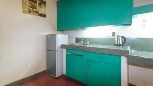 a kitchen with green cabinets and a white refrigerator at RedDoorz at Broadway Court Apartelle Quezon City in Manila