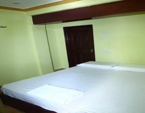 una camera da letto con un letto con lenzuola bianche e una porta di SPOT ON V Guest Inn a Tenāli