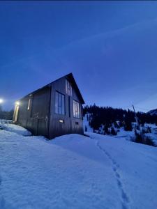 a wooden cabin in the snow in the evening at Cottage SuBree on Goderdzi in Goderdzi