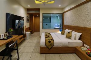 a bedroom with a bed and a desk and a television at Grand Kailash Hotel in Aurangabad