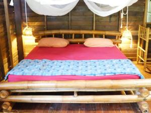 a bed with a wooden frame in a room at Room in Bungalow - Breathtaking Cottage of Koh Pu in Ko Jum