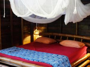 a bed with a red blanket and a net at Room in Bungalow - Breathtaking Cottage of Koh Pu in Ko Jum