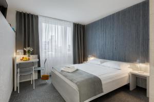 シュチェチンにあるPłonia Resortのベッドと机と窓のあるホテルの部屋