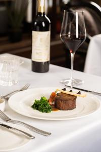 a plate of food on a table with a glass of wine at AMBASSADOR SIGNATURE CRUISE - Lan Ha Bay in Ha Long