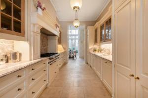 a kitchen with white cabinets and a long hallway at Elegantly Designed Belgravia Townhouse in London