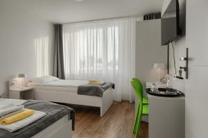 een witte kamer met 2 bedden, een tafel en een bureau bij Płonia Resort in Szczecin
