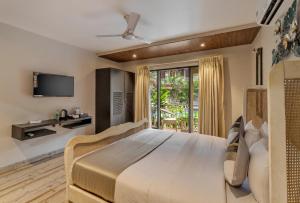 ein Schlafzimmer mit einem großen Bett und einem TV in der Unterkunft Le dando Beach Resort by Orion Hotels in Velha Goa