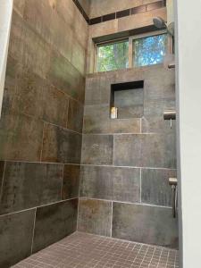 La salle de bains est pourvue d'une douche et d'un mur en pierre. dans l'établissement The Groves at Redway Beach - Craftsman, à Redway