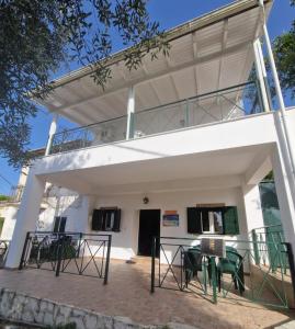 ein Haus mit einem Balkon und Tischen davor in der Unterkunft Villa Korakades in Korakádes