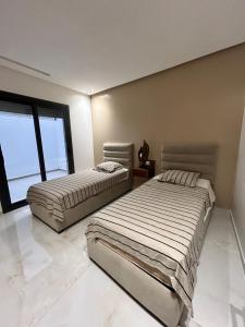Duas camas num quarto com uma grande janela. em Chez Nissrine em Tétouan