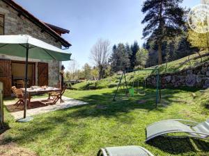a garden with a table and an umbrella and a swing at Appartement La Versanne, 4 pièces, 6 personnes - FR-1-496-280 in La Versanne