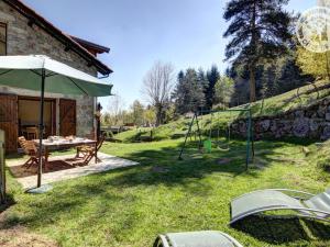 ogród ze stołem, parasolem i huśtawką w obiekcie Gîte et studio avec cheminée, terrasse, salle de jeux et nature préservée à La Versanne - FR-1-496-280 w mieście La Versanne