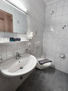 a white bathroom with a sink and a toilet at The Steakhouse - Guest Rooms in Sankt Johann im Pongau