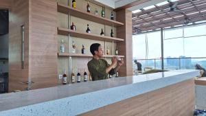 雅加達的住宿－Grand Ametis Hotel Jakarta，男人站在酒吧喝一杯