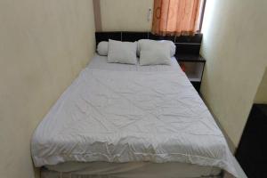 查亞普拉的住宿－OYO 93479 Hotel Jaguar Sentani，一张位于小客房内的床铺,配有白色棉被