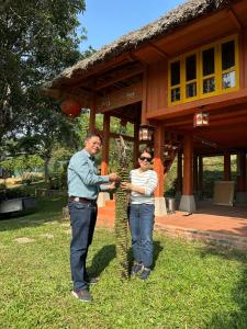 un hombre y una mujer parados frente a un árbol en Pài Bjooc homestay, en Làng Mán