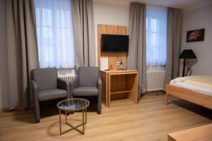 Pokój hotelowy z łóżkiem, krzesłem i telewizorem w obiekcie Hotel & Café Ritter von Böhl w mieście Deidesheim