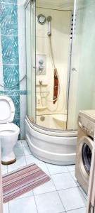 ein Badezimmer mit einer Dusche, einem WC und einer Waschmaschine in der Unterkunft Квартира на Иксанова in Oral