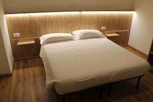 1 cama con sábanas blancas y almohadas en una habitación en Hotel Miramonti, en Chiesa in Valmalenco