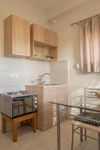 a kitchen with a stove and a glass table at Studios Anna Maria in Kapetanianá