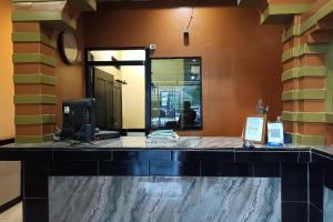 a lobby with a desk with a computer and a mirror at OYO 93485 Hotel Kenzie Sentani in Jayapura