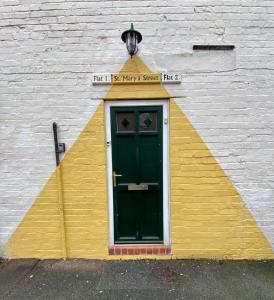 a building with a green door and a yellow wall at Central Crewe - Modern 1BR Haven in Crewe