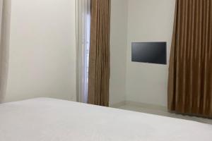 - une chambre avec un lit et une télévision murale dans l'établissement OYO 93485 Hotel Kenzie Sentani, à Jayapura