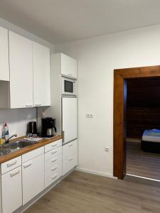 a kitchen with white cabinets and a sink and a door at Gasthof Löwen in Pfronten