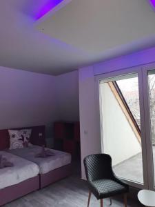 een slaapkamer met een bed, een stoel en een raam bij Бутик хотел ресторант брасери Сажитариус in Kyustendil