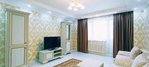 ein Wohnzimmer mit einem TV und einem Sofa in der Unterkunft Comfortable apartment on Sarayshyq street 7-1 in Astana