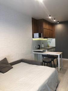 a bedroom with a bed and a table and a kitchen at Сучасна, стильна студія біля ВДНГ in Kyiv