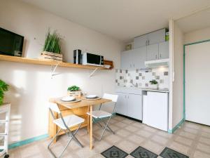uma pequena cozinha com uma mesa de madeira e cadeiras em Studio Saint-Lary-Soulan, 1 pièce, 4 personnes - FR-1-296-488 em Saint-Lary-Soulan