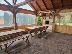 - un pavillon avec des tables et des bancs en bois sur une terrasse dans l'établissement Ildikó Vendégház Szabolcs, à Szabolcs