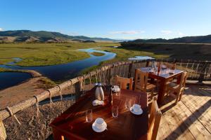 a table and chairs with a view of a river at ViaVia Harganat Lodge 