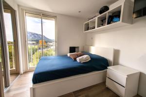 a bedroom with a blue bed and a large window at Suite vue sur mer in Marseille