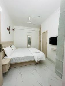 a white bedroom with a bed and a flat screen tv at Vista Express in Dehradun