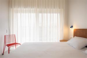 - une chambre avec un grand lit blanc et une chaise rouge dans l'établissement Kallithea Apartments by Olala Homes, à Athènes